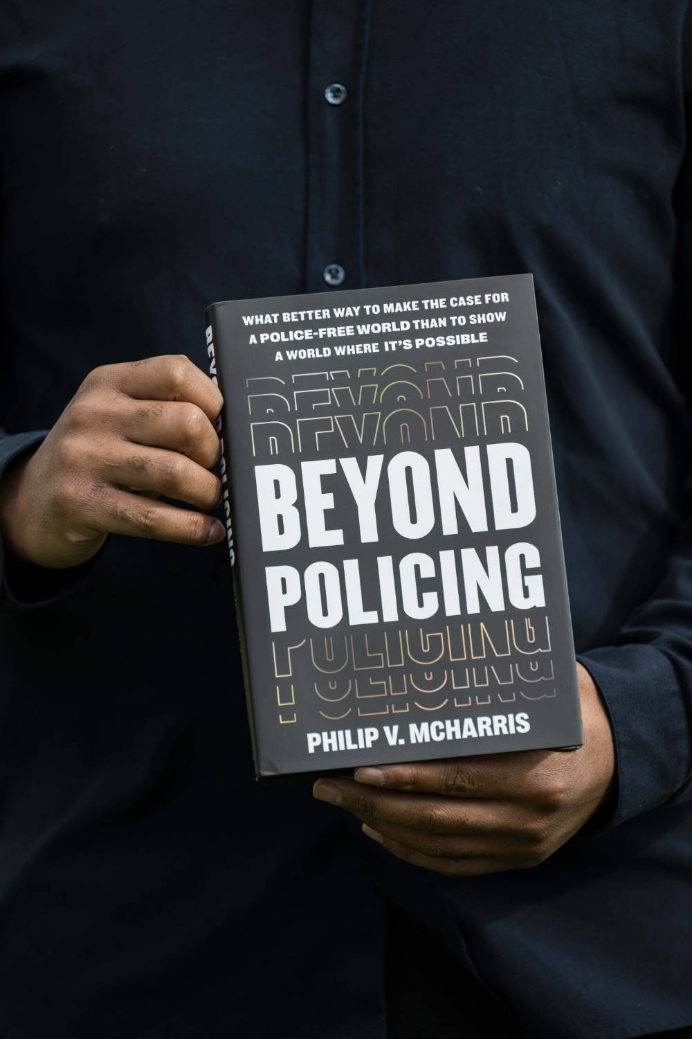Close-up of Philip V. McHarris's hands holding a copy of his book, "Beyond Policing."
