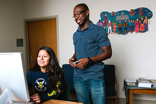 A student looking at a computer with a staff person.